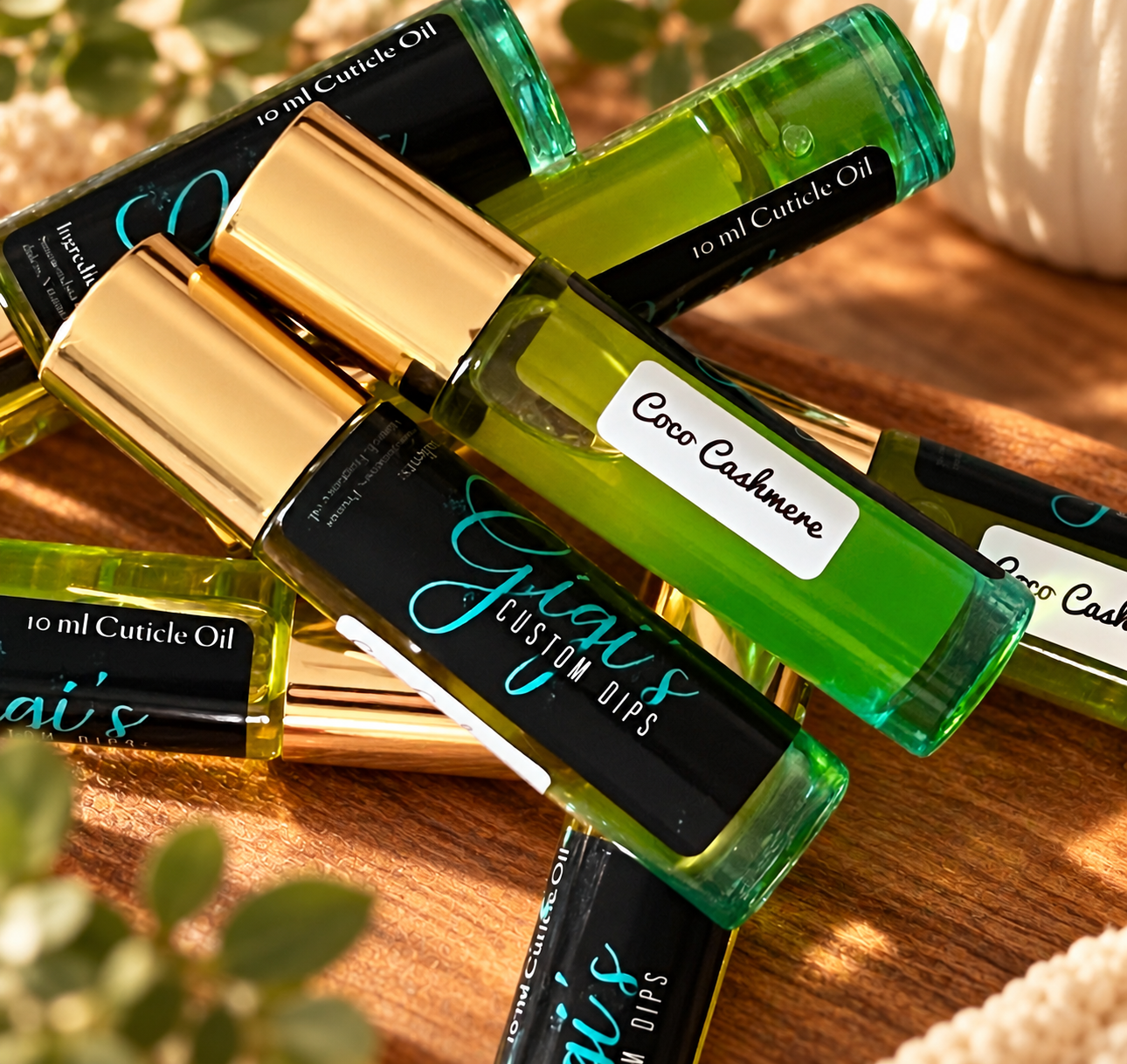 Styled product photo of Coco Cashmere cuticle oil with warm wood, greenery, and cream accents