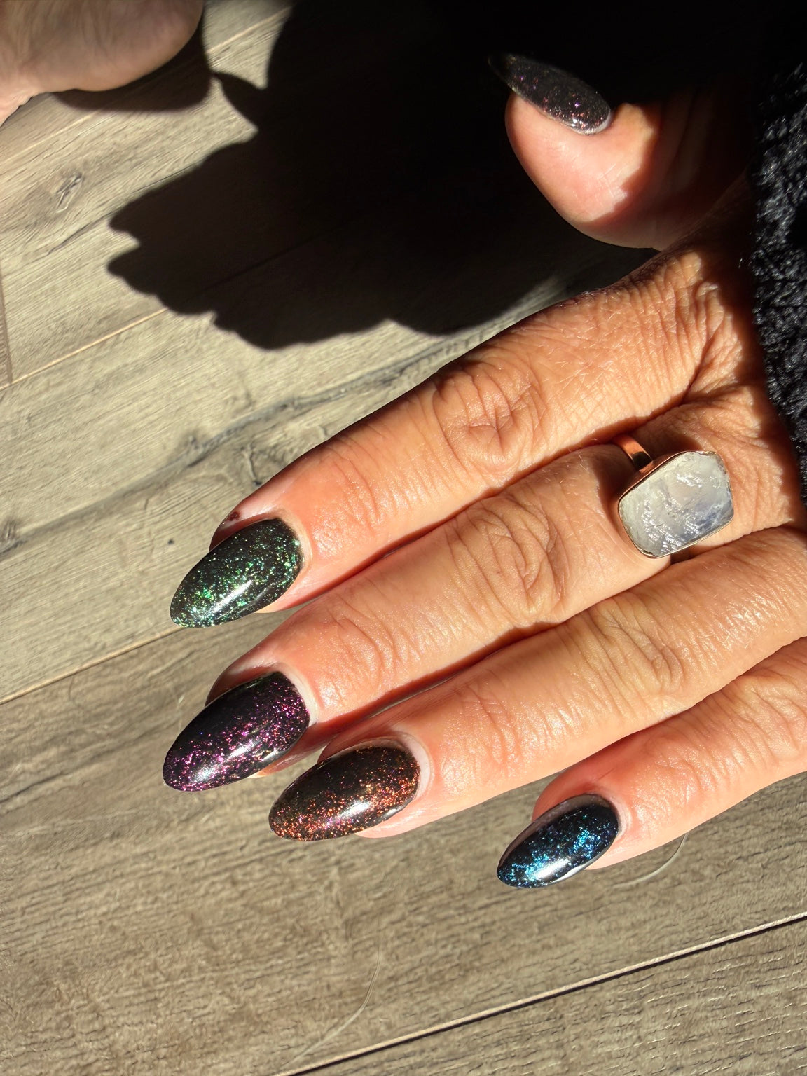 Black chameleon flake manicure featuring Zero Regrets, natural-light view 2