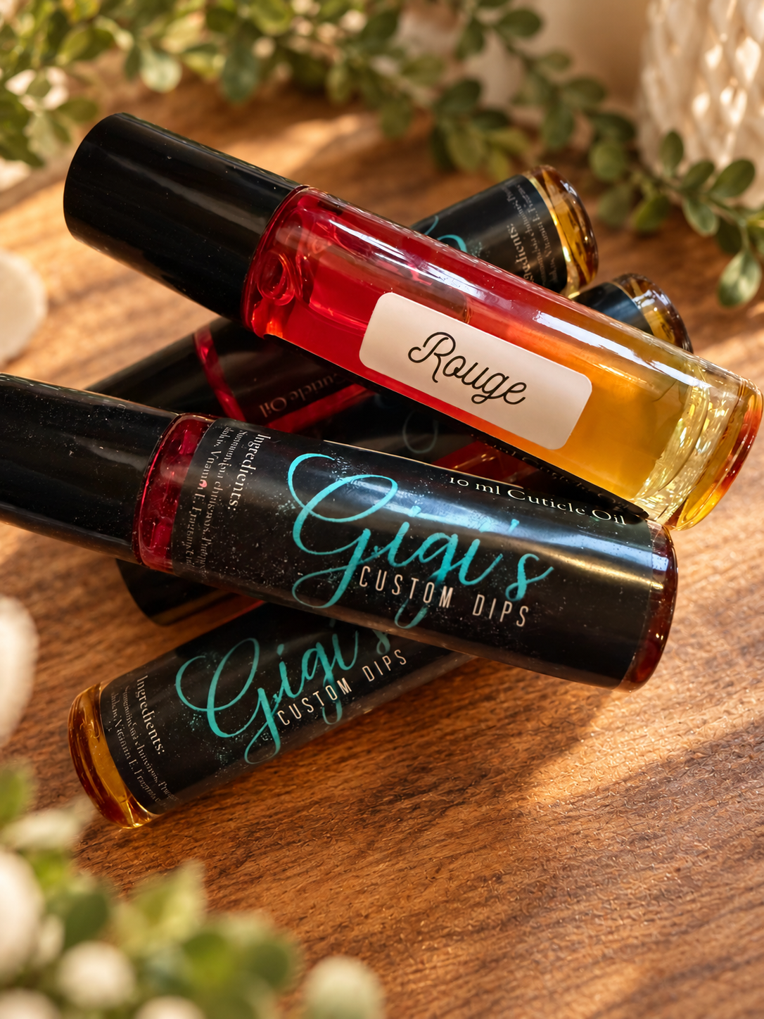 Styled product photo of Rouge cuticle oil with warm wood, greenery, and cream accents