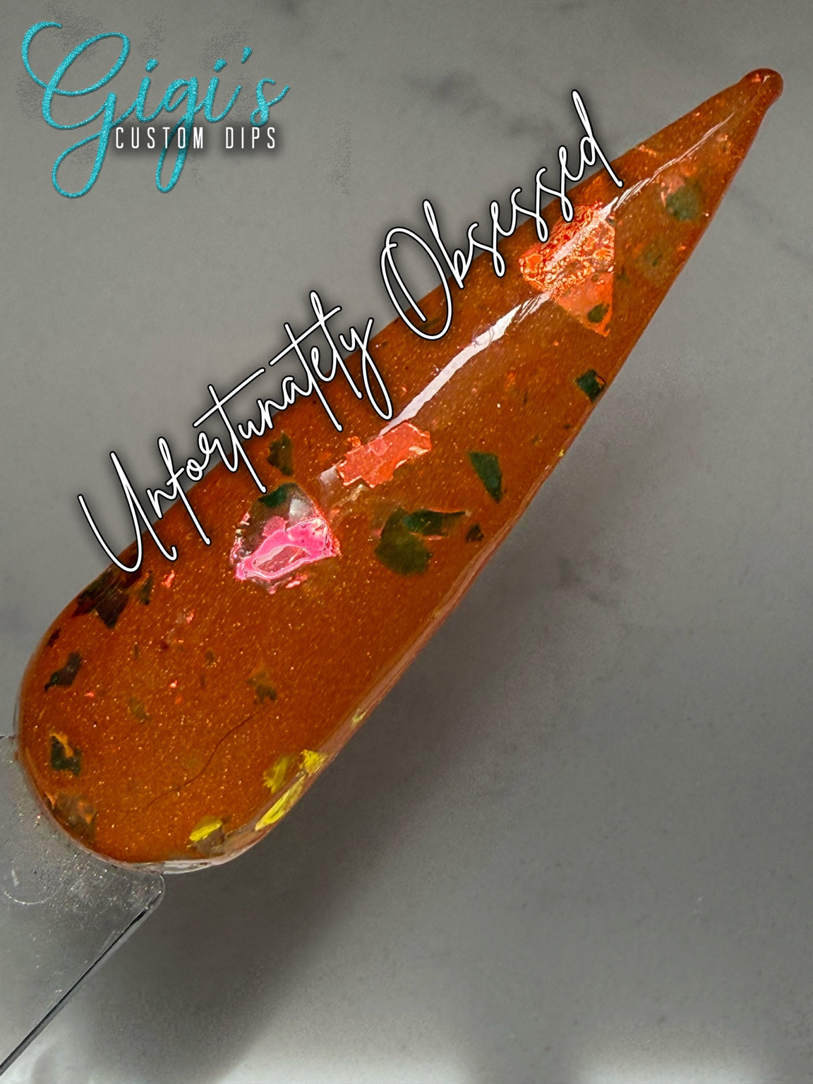 Labeled Unfortunately Obsessed orange dip powder swatch with green, gold, bronze and pink colour-shifting flakes