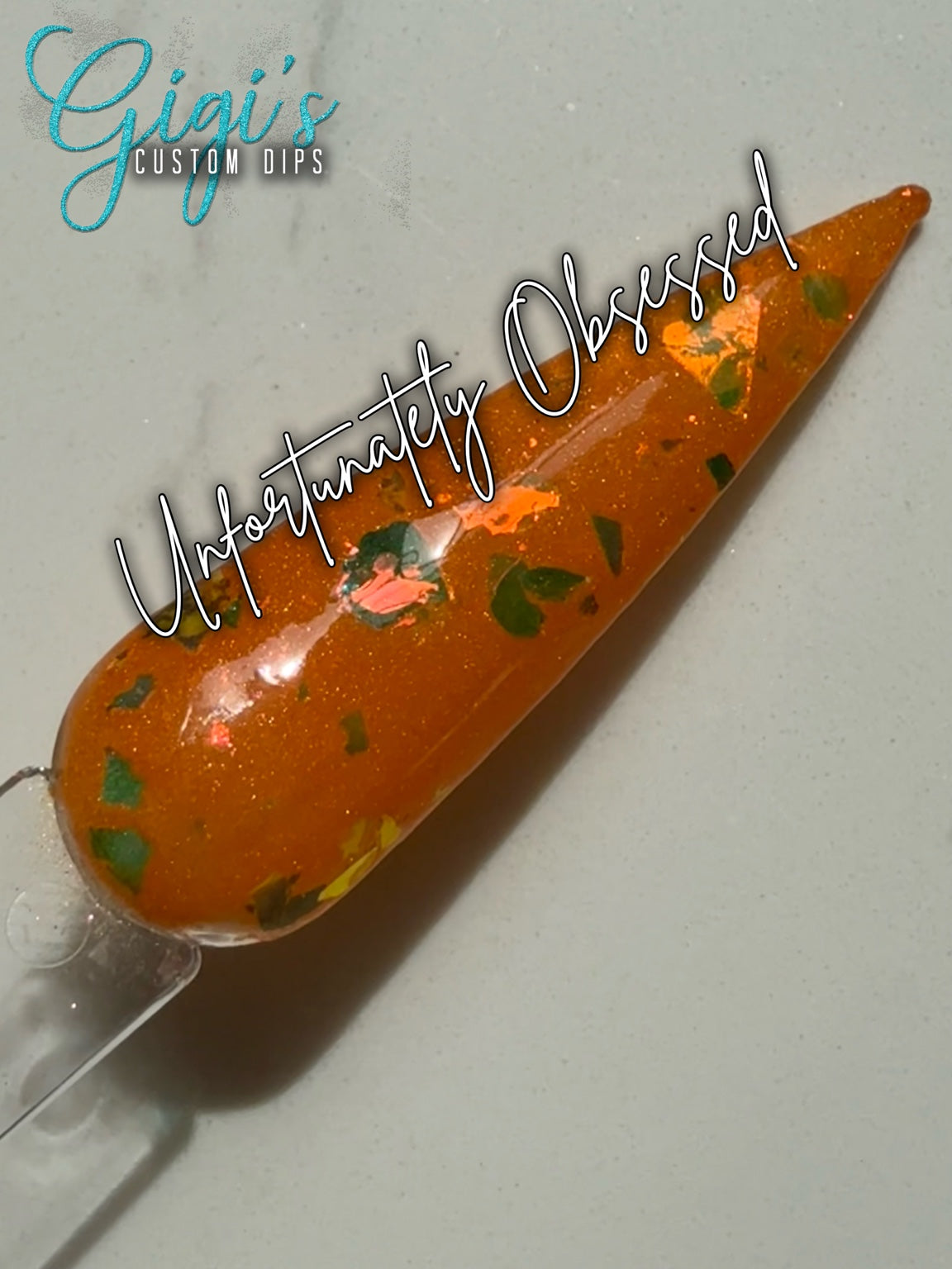 Labeled Unfortunately Obsessed orange dip powder swatch with green, gold, bronze and pink colour-shifting flakes